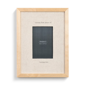 A simple light wood frame with a cream fabric backing that reads "twenty five years of loving you" around a photo insert.