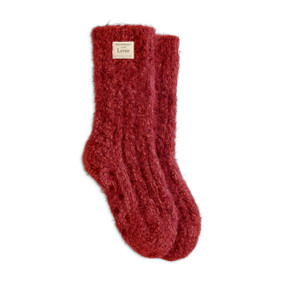 A pair of red fuzzy socks with a small cream fabric Giving Collection tag attached.