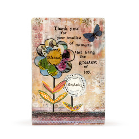A ceramic plaque with a collage style of background and flowers, and reads "Thank you for your smallest of moments that bring the greatest of joy".