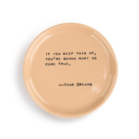 A small circular, peach colored keepsake dish with a sentimental message about your dreams in black typewriter font.