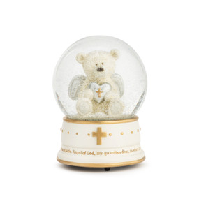 An ivory snowglobe, with gold accents, such as dots and a cross, and has an Angel of God message about the bottom. filled with glitter and an ivory bear holding a silver and gold heart.
