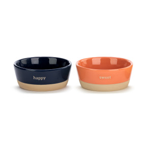 A set of two ceramic ice cream bowls, each with a thin tan base. One dark blue and reads happy". One coral and reads "sweet"."