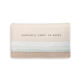 A beige and ivory spoon rest with blue waves and "happiness comes in waves" engraved.
