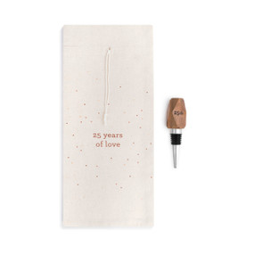 A white wine bottle bag with red dots that reads "25 years of love" beside a wooden wine stopper with "25th" engraved.