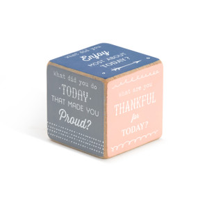 A jumbo sized wooden dice with different color painted sides, and a family conversation starter, such as What are you thankful for today?" in white font."