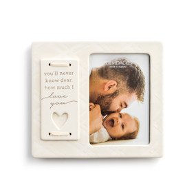A textured cream picture frame with a plate that reads you'll never know dear, how much I love you" and has a heart shaped cutout. Enclosing a picture of a father and a baby."