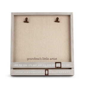 A light wooden, customizable picture frame with two bronze clips, and moveable date squares. With a tan backing and reads "grandma's little artist" in brown font.