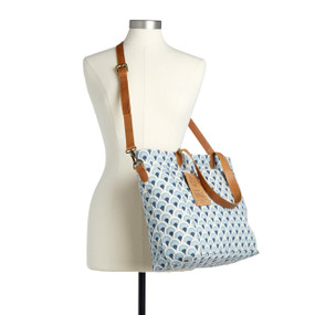 A blue and white tote bag with a scallop design that has leather handles and a shoulder strap displayed on a mannequin.