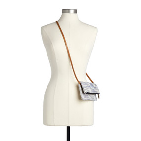 A navy pinstripe cross body bag with a zipper and leather strap displayed over the shoulder of a mannequin.