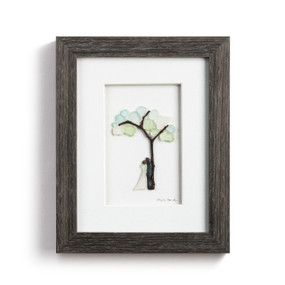 A pebble scene of a newly couple under a tree, enclosed in a dark wooden frame.