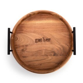 Top down view of a round wood tray that says "gather" with two black metal handles.