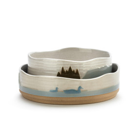 Two ceramic stacking bowls one set inside the other depicting a lake theme with ducks and water.
