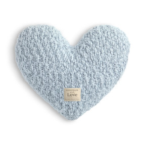 A light blue heart shaped Giving Collection pillow with a small cream Giving Collection fabric tag attached.