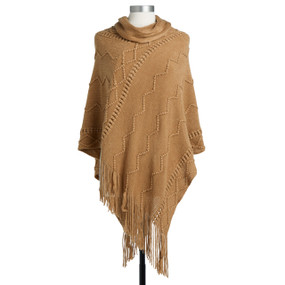 A burnt orange poncho, textured with an assortment of lined patterns, and with a fringed bottom edge. Placed on a black and white mannequin.