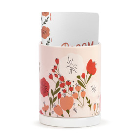 The front view of a peach planter decorated with orange and red flowers that has a paper journal inside.