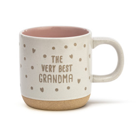 A cream ceramic handled mug that says "The Very Best Grandma" in brown along with dots and hearts. The inside of the mug is pink.