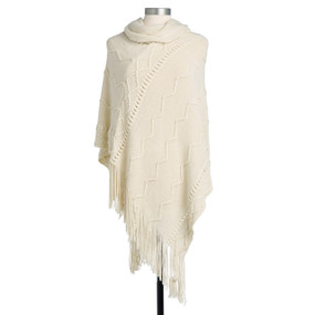 A soft cream poncho, textured with an assortment of lined patterns, and with a fringed bottom edge. Placed on a black and white mannequin.