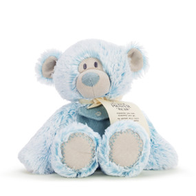 A light blue plush bear sitting down with a corduroy pocket on his chest and wearing a product tag tied with a cream ribbon.