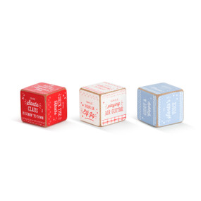 A set of three small wooden dice that work together to form a Christmas Karaoke task. A red dice with holiday songs on each side, a white dice with a direction such as "while playing air guitar", and a blue dice with a tone of voice direction, such as "giddy and giggly".