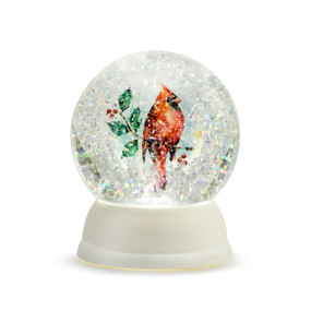 An illuminated snow globe with a white base, and filled with a painting of a cardinal on a holly branch, and glitter crystals.