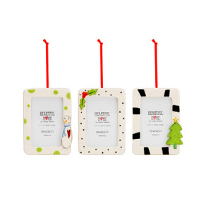 A set of three white, ceramic picture frame ornaments. One with green polka dots and a snowman, one with small black polka dots and holly leaves, and one with black striped and a Christmas tree. Each with a red ribbon string.