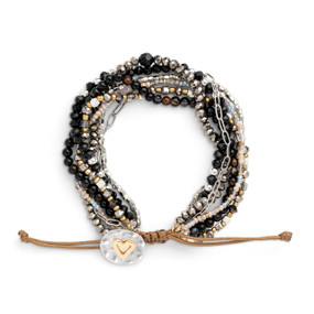 An adjustable bracelet made of multiple stands of various black and silver beads and a mixed metal charm with a gold heart.