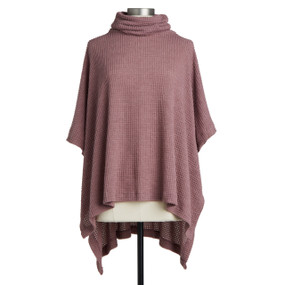A dusty rose colored waffle knit poncho displayed on a mannequin.
