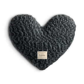 A charcoal colored heart shaped Giving Collection pillow with a small cream fabric tag for the Giving Collection.