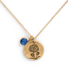 Detail shot of the charms on a delicate gold necklace with a round gold charm with the birth flower for September and a separate birthstone.