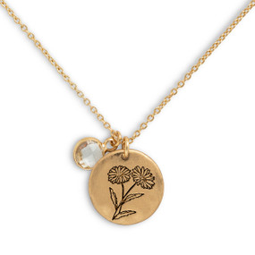 Detail view of the charms on a delicate gold necklace with a round gold charm with the birth flower for April and a separate birthstone.
