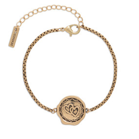 A gold metal bracelet that has a round metal charm with two intertwined hearts.