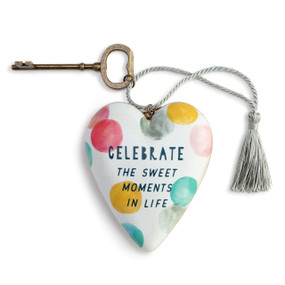 Heart shaped sculpture with a silver tassel and metal key attached. The heart has colored dots and says "Celebrate the Sweet Moments in Life".
