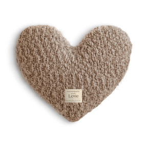 A camel colored heart shaped Giving Collection pillow with a small cream fabric tag for the Giving Collection.