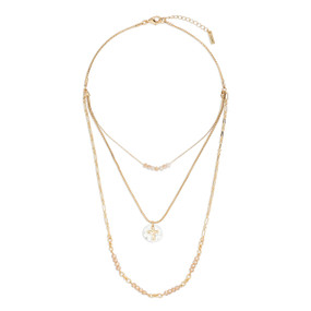 A gold three strand necklace with champagne colored beads and a charm that is a mixed metal circle with a gold cross.
