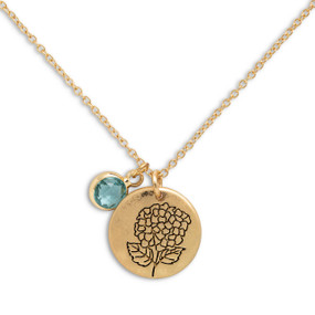 Detail view of the charms on a delicate gold necklace with a round gold charm with the birth flower for March and a separate birthstone.