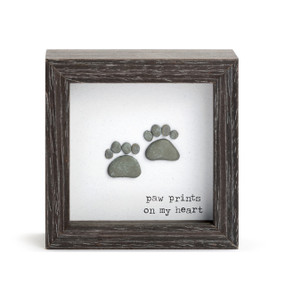 A square dark wood shadow box with two stone paw prints that says "paw prints on my heart".