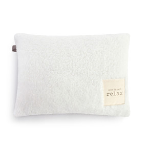 Rectangular white sherpa pillow with a fabric tag in the lower right corner that says "note to self: relax".
