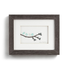 Dark wood framed wall art of four birds on a branch with leaves made of pebbles.