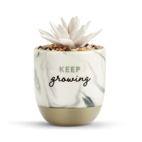 White and black marble planter that says "Keep growing" and has a gold base with a fake white succulent inside that works as a diffuser.