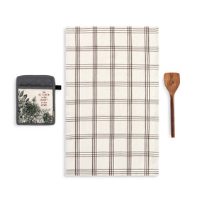 A white towel that has black lines with a gray floral hot pad that says "the Kitchen is the Heart of this Home" and wood spatula.