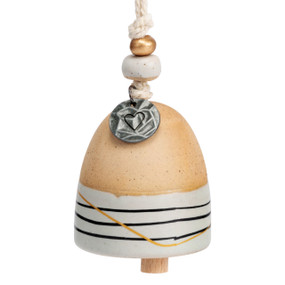 A mini tan and cream bell with black horizontal lines on the bottom half. There are beads and a metal token at the top of the bell.