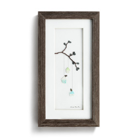 A dark wood framed wall art of little bird houses hanging from a branch made out of pebble art.