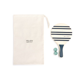 A paddle ball set with two blue and cream paddles, two green balls and a cream fabric drawstring bag.