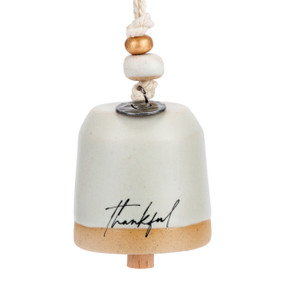 A mini cream bell that says "thankful". There are beads and a metal token at the top of the bell.
