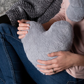 Close up of a woman holding a gray heart shaped comfort pillow.