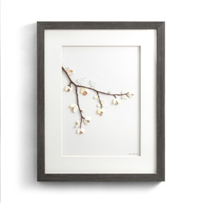 A gray wood framed image of a tree branch with two birds and flowers made of pebbles.