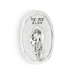 An oval silver metal visor clip with the image of an feathered wing that says "by my side".