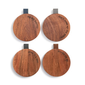 Four different round wood coasters with cute sayings along the edge. They each have a leather tab in a different color on the edge.