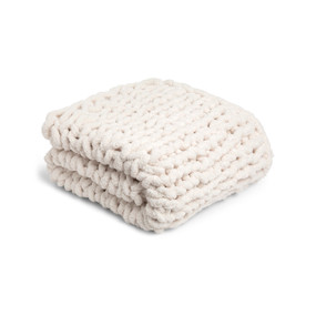 A cream chunky knit blanket folded and displayed on a white background.