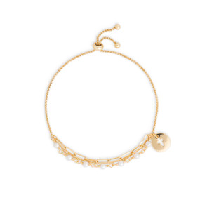 A gold chain bracelet with white and gold beads. It also has a round gold token with a cross cutout.